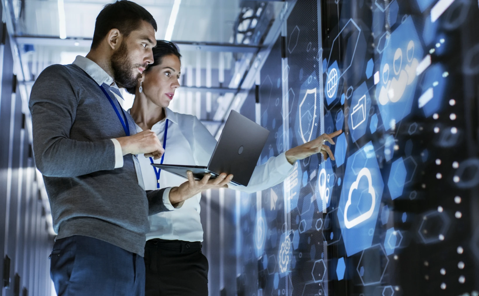 Two IT professionals in a data center examining a holographic cloud interface